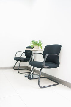 Two black office chairs in a corridor or waiting area, table with a small green plant.