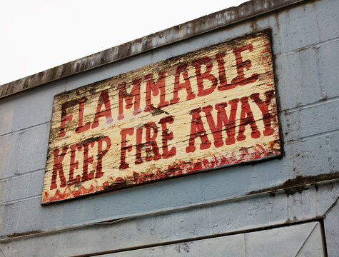 A painted warning sign on the exterior of a building. Flammable, keep fire away.