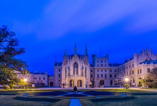 Lednice Castle, a large gothic built fortified house and formal gardens, a UNESCO world heritage site, lit up at night.