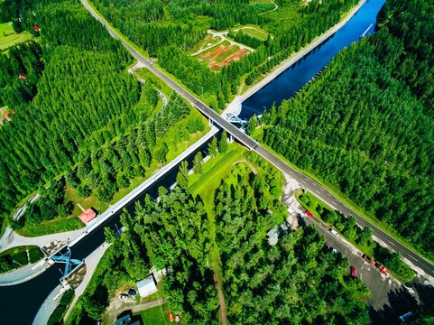Aerial view showcasing the intersecting river and road surrounded by dense green forestsin Finland