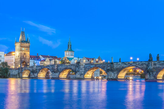 The Charles Bridge over the River Vtlava with buildings lit up at night.