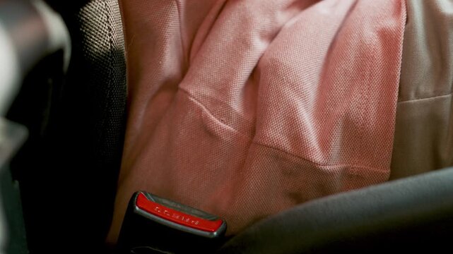 Man use seatbelt and drives with intent, safe drivin seatbelt buckle with a red release button secured in a vehicle interior, showcasing the safety feature and design elements of automotive seating.