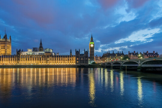 Big Ben and Parliament Buildings at Sunset, dusk and the lights of the building reflecting in the river Thames.
