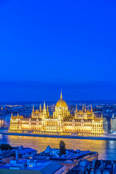Budapest, the Hungarian Parliament building, Orsz&aacute;gh&aacute;z, neo-Gothic architecture, dome and stone pinnacles, lit up at dusk, by the River Danube.