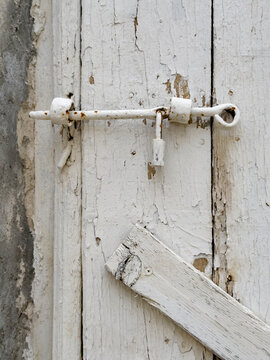 Weathered Door, close up of a wooden door with a metal bolt and padlock, peeling white paint.