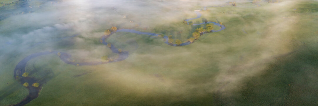 Meandering Suica River in the Duvanjsko Polje, the Duvno field valley, and a bow of fog in the air, view from above.