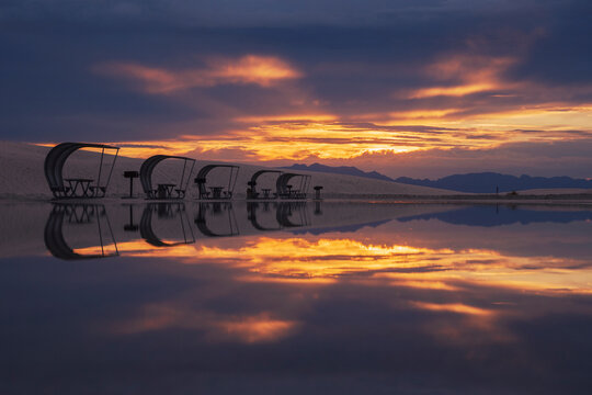 Rows of curved sun shelters, cabanas with seats for visitors to the White Sands national park at sunset.
