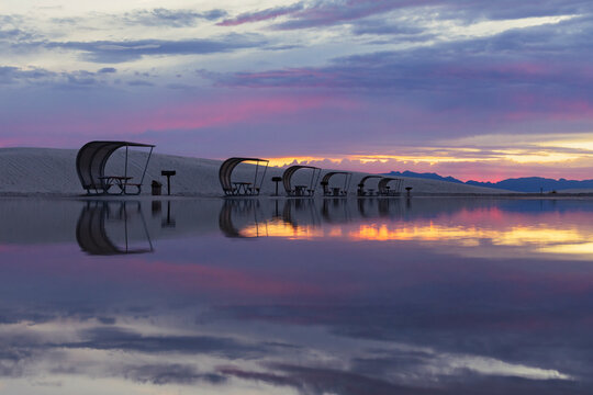 Rows of curved sun shelters with seats for visitors to the national park, on the white sands, at sunset, White Sands National Park