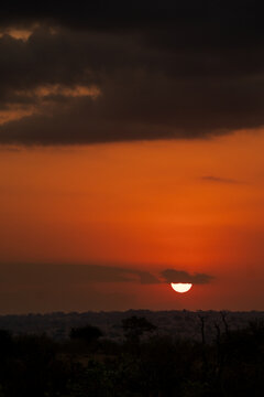 Landscape at Sunset, a dramatic, orange and red sunset with a clear horizon line and dark clouds above.