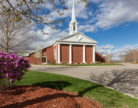 A traditional styel historic church building with a white painted spire and bell tower, portico and columns.