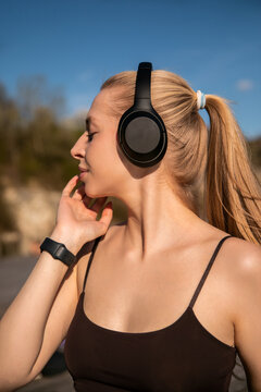 Attractive woman relaxing with favorite playlist after exercise. Beauty woman embracing healthy outdoor lifestyle naturally. Fitness wellness concept