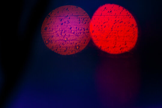 Blurred headlights and tail lights at night, two light spots, red and pink,