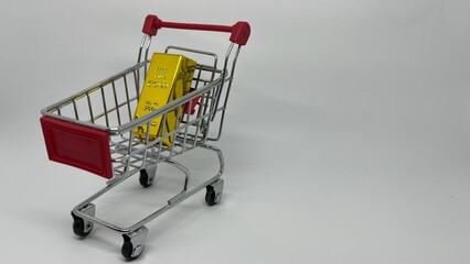 Mini shopping cart filled with gold bars on neutral background © fuad chasan