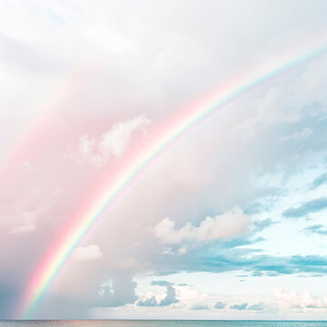 Beautiful double rainbow in a soft pastel pink and blue sky with clouds