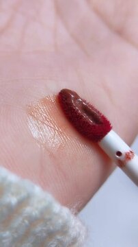 Extreme close up of lip tint brush being applied onto skin. Beauty content concept for makeup tutorial or product review.