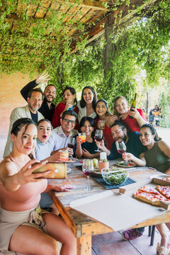 photo selfie with mobile phone of large group of friends or multi generation family eating and having a dinner in a terrace party in Mexico Latin America, portrait of hispanic people