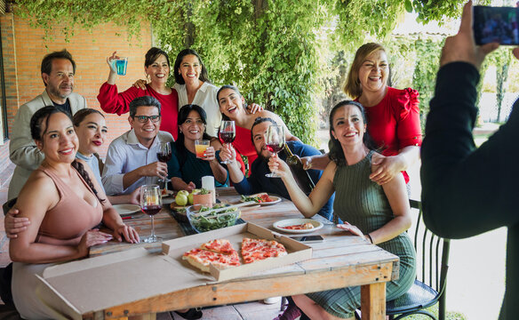 photo selfie with mobile phone of large group of friends or multi generation family eating and having a dinner in a terrace party in Mexico Latin America, portrait of hispanic people