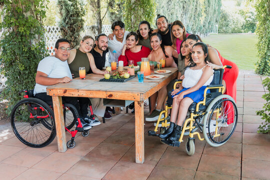 large group of friends with people with disabilities and wheelchair eating and having a dinner in a terrace party in Mexico Latin America, hispanic diverse and multicultural people 