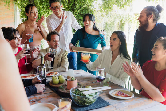 large group of latinos friends or multi generation family eating pizza and having a dinner in a terrace party in Mexico Latin America, hispanic diverse, multi age and multicultural people