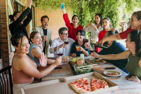 large group of latinos friends or multi generation family eating pizza and having a dinner in a terrace party in Mexico Latin America, hispanic diverse, multi age and multicultural people