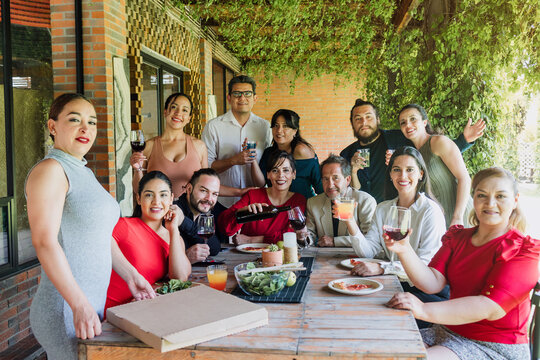 large group of latinos friends or multi generation family eating pizza and having a dinner in a terrace party in Mexico Latin America, hispanic diverse, multi age and multicultural people