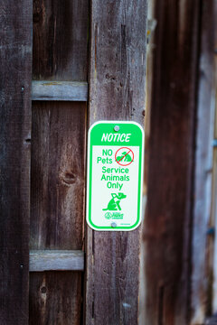 No Pets, Service Animals Only Sign on a wooden post outside a building, an accessible space for assistance animals with their owners.