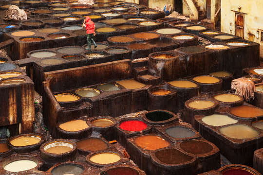 Chouara Tannery in Pouring Rain, elevated view of the dye pits full of leather hides, workers at the site.