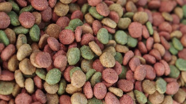 Close up rotation of colorful dry cat food pellets background texture