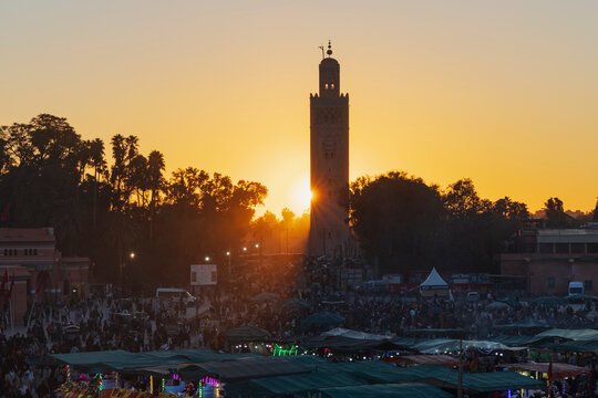 Koutoubia Minaret at Sunset, a tall tower silhouetted against the sun at dusk.