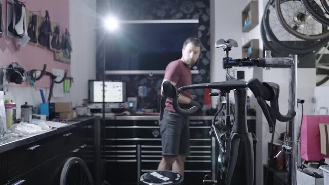 Skilled male tech fixing carbon cockpit on expensive black road bike. Professional workshop environment, premium bicycle maintenance, high-utility service, mechanical engineering and repair job.