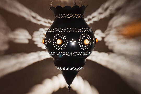 A traditional brass lamp with open metal fretwork pattern throwing patterned shadows.