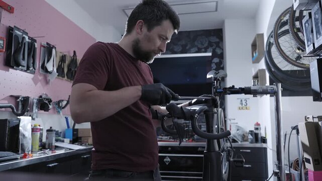 Master mechanic performing precision tuning on expensive black carbon road bike. Premium cycling gear service, mechanical tools workflow, expert maintenance and assembly in specialized workshop.