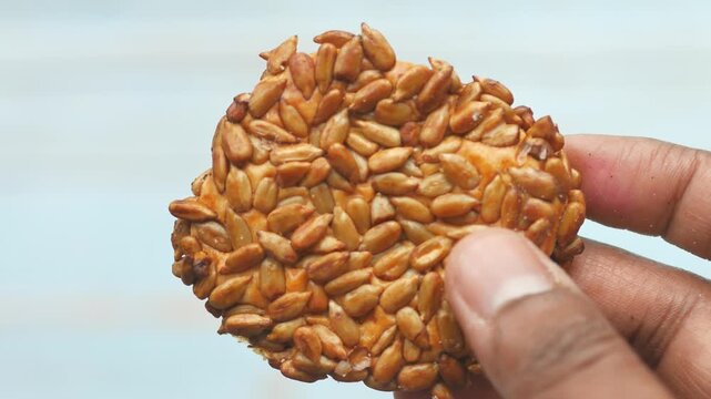Close up shot of hands breaking a sesame seed cookie in half