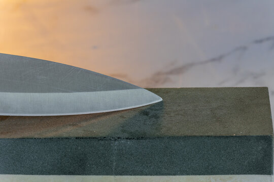 knife blade sharpening on whetstone closeup