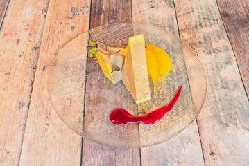 Gourmet foie gras slices garnished with microgreens, fruit puree, and berry sauce on a textured glass plate. © Toyakisfoto.photos