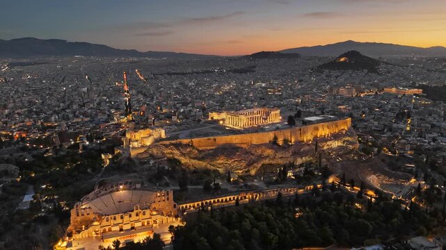 Acropolis of Athens illuminated at sunset with city panorama and ancient temple, aerial drone view of famous landmark at dusk. Sunset over Athens Acropolis with illuminated Parthenon