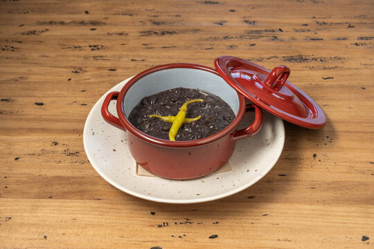 Black Bean Stew with Yellow Chili Pepper Served in a Red Cocotte on Rustic Wood