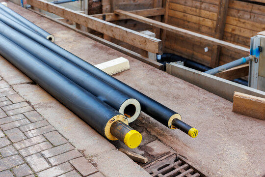 New modern insulated urban pipeline installation construction site  exposed underground pipes in shored trenches. Insulated steel pipes lie connection engineering infrastructure upgrade work