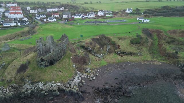 Drone tracks over Dunure Castle ruins above rocky coast, Ayrshire village.