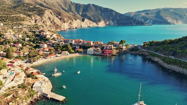 Aerial view of Assos village bay with yachts anchored in turquoise water, colourful houses on Kefalonia island in Greece. Assos village on Kefalonia island, colorful Greek houses surrounded by sea