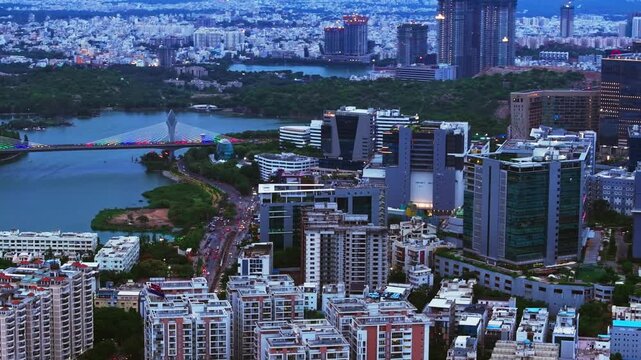 illuminated cable bridge with Durgam Cheruvu, skyline, corporate building and apartments at hitec city, madhapur, hyderabad, telangana, india. evening time, semi circle shot, drone shot, 4k.