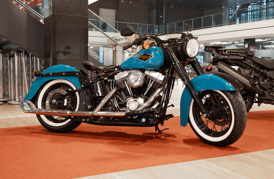 Harley-Davidson cruiser motorcycle with turquoise finish and classic whitewall tires showcased at a motorcycle exhibition.