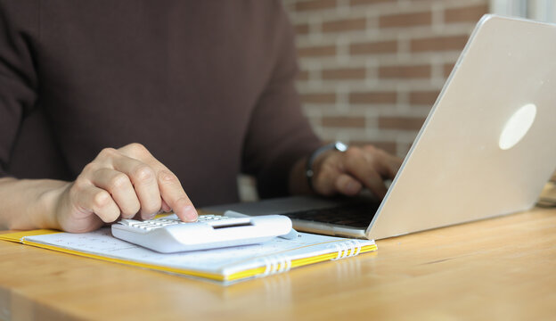 close up man hand press on calculator and check invoice letter from bank to check about debt and spending monthly for people lifestyle and inflation economic concept