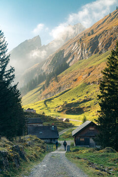 Switzerland fall mountain scenery with hikers on trail along traditional chalets, Seealpsee, Appenzell, Switzerland