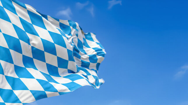 Blue and white diamond patterned Bavarian flag waving vigorously in strong wind against clear blue sky background on sunny day. Carnival Oktoberfest festival celebrating concept with copy-space.