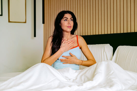 Woman sitting in the bed in the morning and making breathing exercises