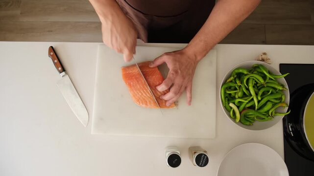 Professional cook preparing a meal by cutting fresh salmon and pulling out fish bones
