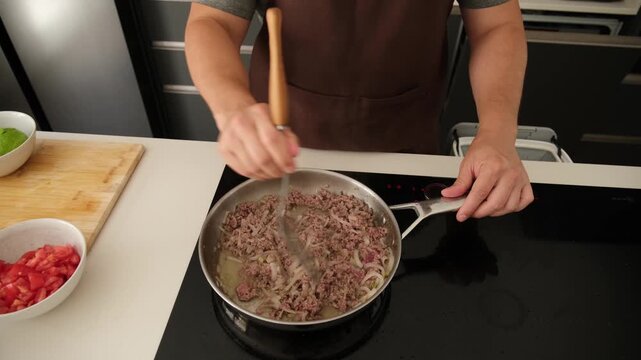 Professional chef preparing a bolognese sauce with minced meat in a modern kitchen