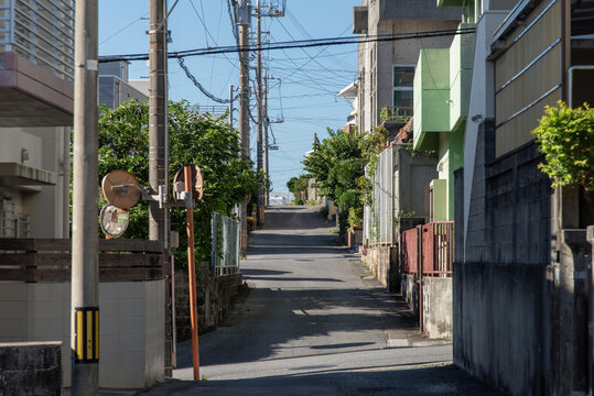 電柱や家々の影が道路にある天気の良い街の直線の路地裏の道
