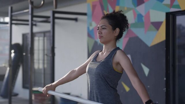 South Asian female athlete performs PVC shoulder pass throughs with a dowel rod during shoulder mobility training. Tracking shot with push in and pull out camera motion. Collection: WORKOUTSERIES2026